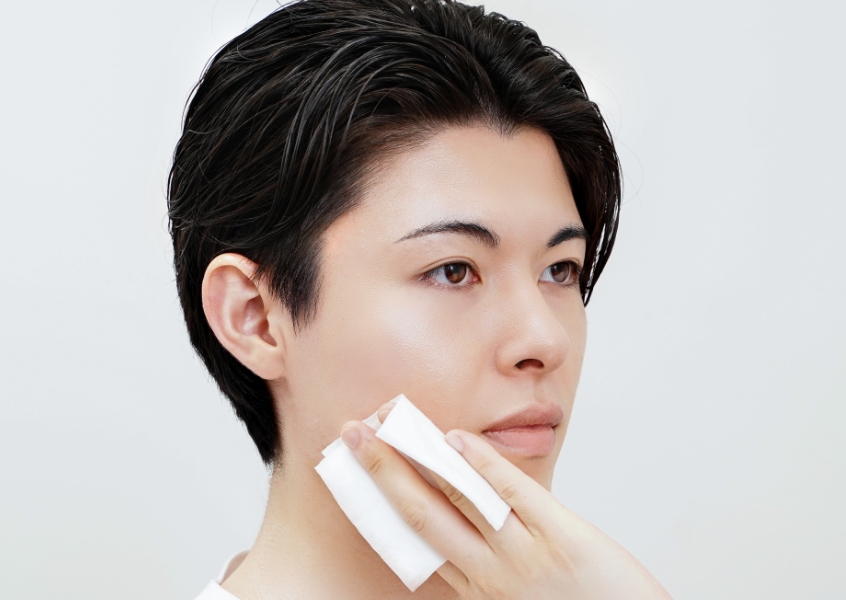 シートで顔を拭く男性