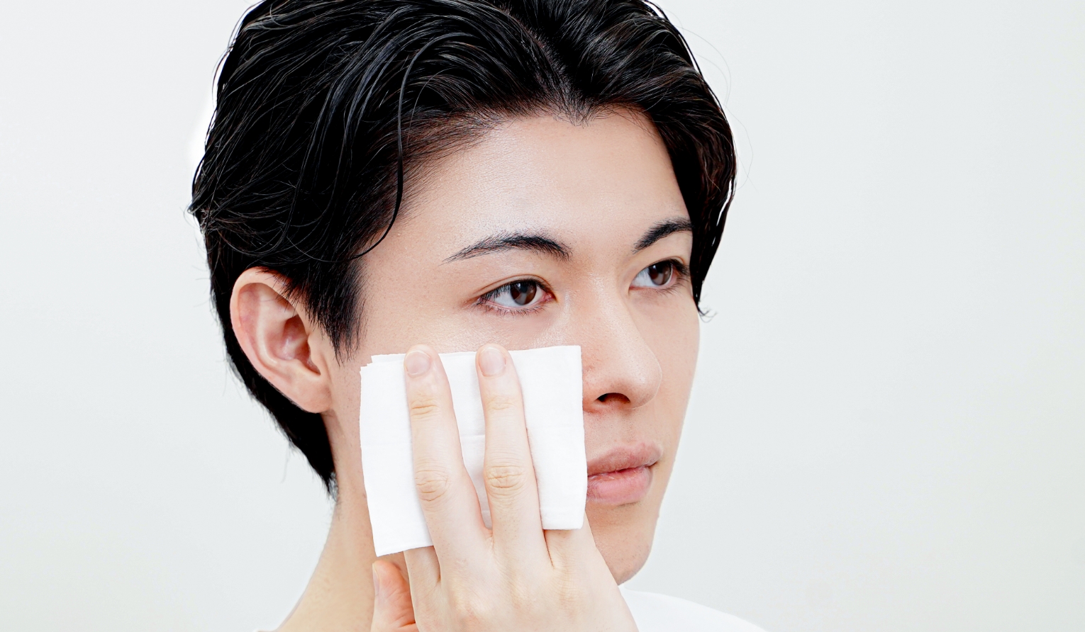 シートで顔を拭く男性